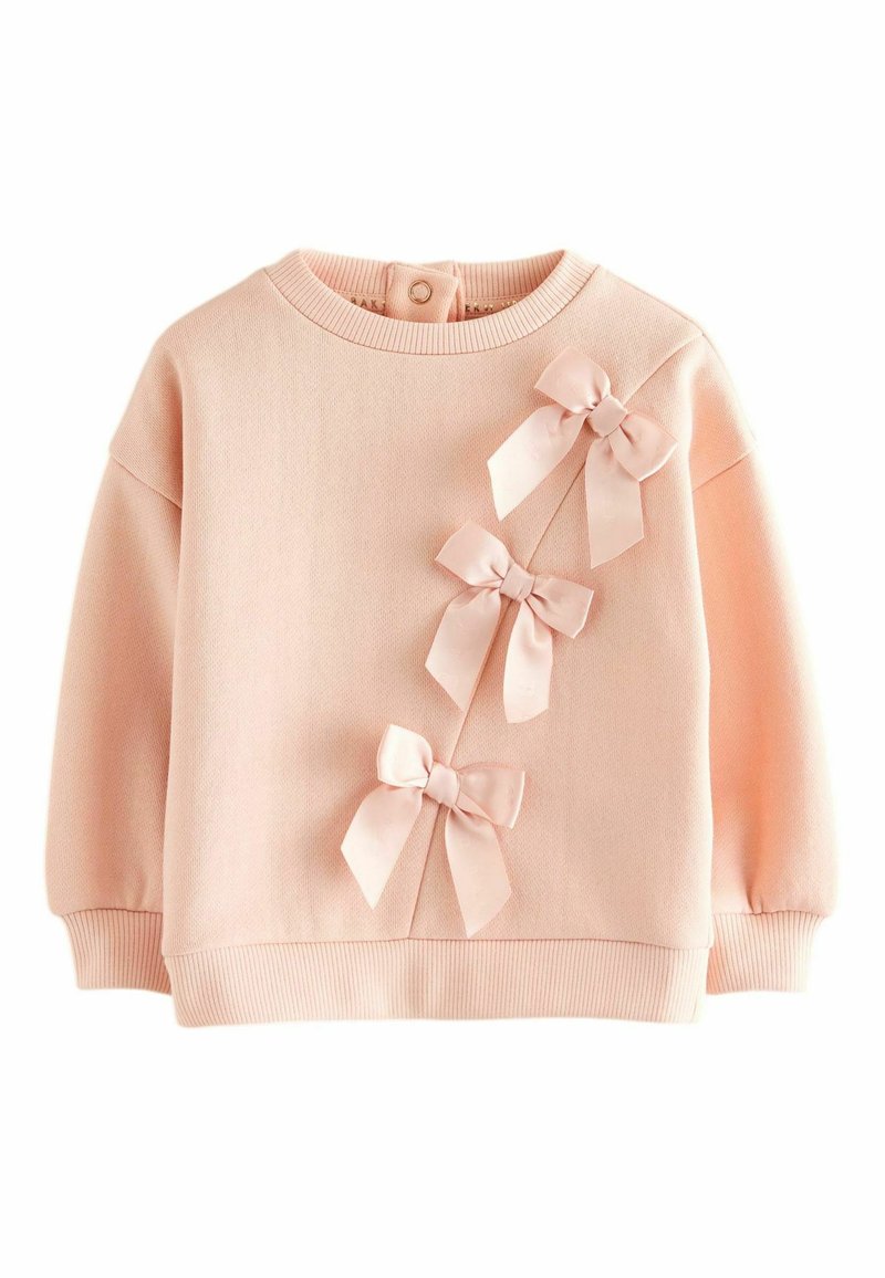 Sudadera rosa claro hecha de tela suave, con tres lazos de satén en el frente y puños y dobladillo acanalados. Cierre trasero con botones.