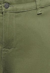 Olivgrüne Denim-Hose mit glatter Textur, Knopfverschluss und sichtbaren Steppnähten. Mit Fronttasche und Bund ausgestattet.