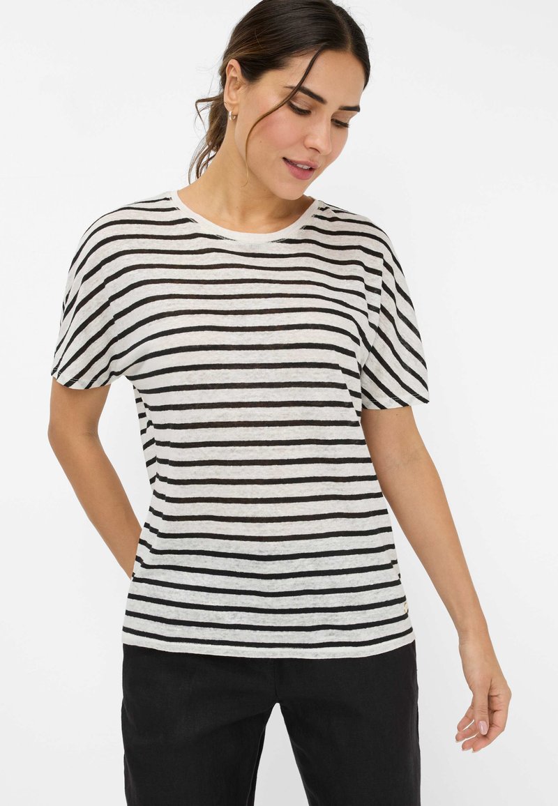 Stripet kortærmet t-shirt i lys creme med sorte vandrette striber, rund halsudskæring og afslappet pasform. Båret med sorte bukser.