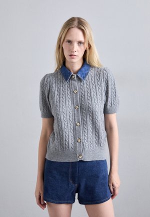 Gray knit cardigan with cable pattern, short sleeves, and denim collar. Features gold buttons and fitted waist. Worn with denim shorts.