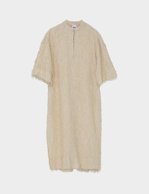 Haljina krem boje, širokog kroja, od teksturiranog, mekanog materijala. Ima kratke rukave, okrugli izrez i ravni kroj. Bez kopčanja.