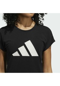 Černé tričko s velkým bílým logem Adidas obsahujícím trojúhelníkový design. Měkký materiál, krátké rukávy a klasický kulatý výstřih.