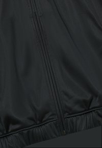 Černá bunda s hladkou, tkanou strukturou, vpředu na zip a elastickým lemem. Jednoduchý design bez viditelných vzorů nebo akcentů.