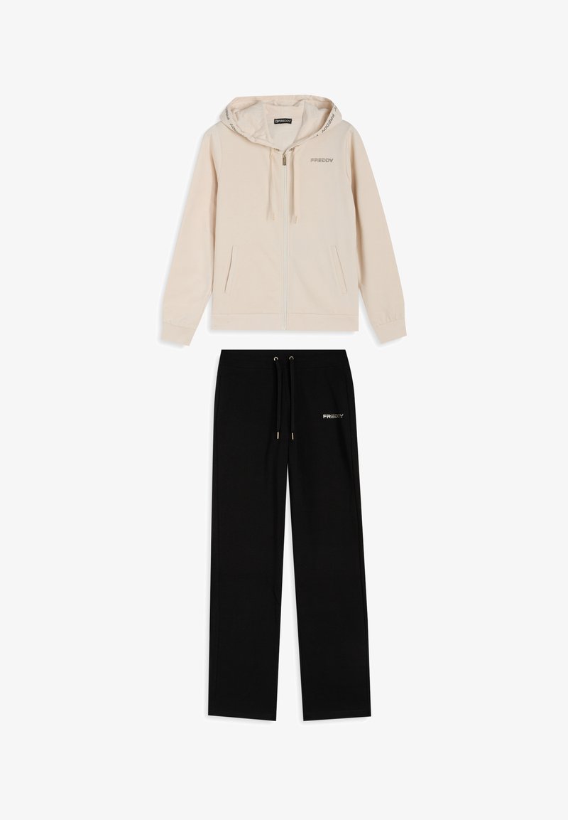 Sudadera con capucha beige con cremallera, cordón y logo; pantalones negros con cintura elástica y logo; ambos en un material suave y liso.