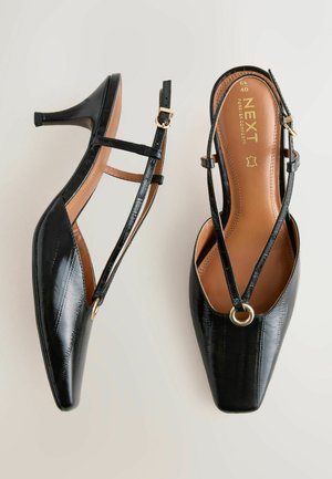 Zwarte slingbackhakken van lakleer met spitse neus, enkelbandje, gouden hardwaredetails en een gestructureerde afwerking.