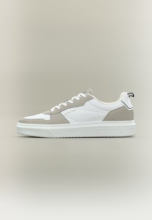 Zapatilla blanca de corte bajo con superposiciones de ante gris claro, cordones blancos, suela gruesa y texto "GAP EST 1969" en el panel lateral.