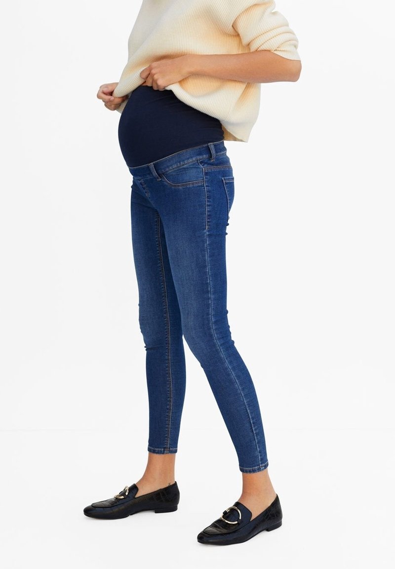 Jeans ajustados de maternidad en denim azul oscuro con un diseño ceñido. Cuentan con una cinturilla elástica para adaptarse a una barriga en crecimiento.