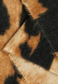 Tierdruckstoff mit einer Mischung aus braunen und schwarzen Texturen. Weiche, flauschige Oberfläche mit einem Muster aus unregelmäßigen Formen. Die Kanten wirken ausgefranst.