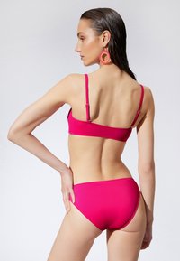 Różowy zestaw bikini z bandeau topem z regulowanymi ramiączkami i klasycznymi majtkami. Materiał wydaje się gładki i elastyczny.