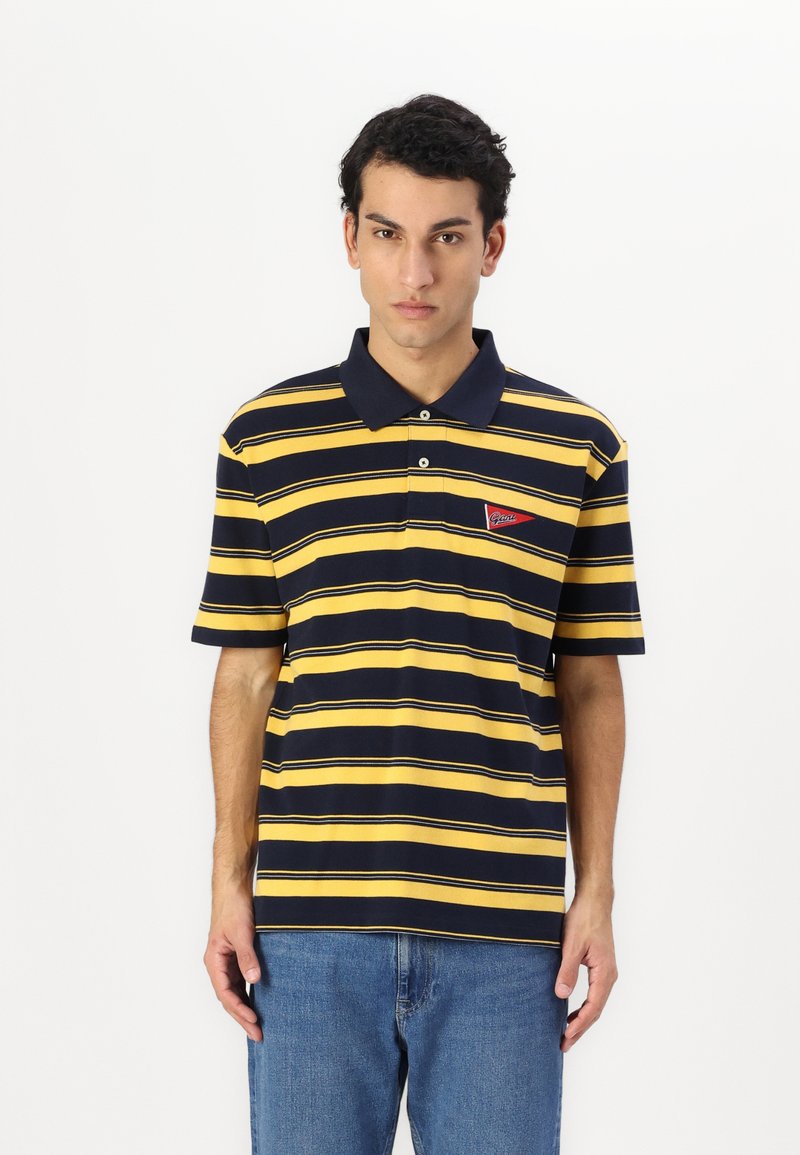 Marineblå og gulstribet polo-shirt med krave, korte ærmer og en lille rød mærke på venstre side.