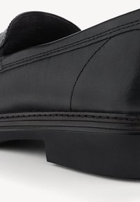 Zwarte leren schoen met een laag profiel, voorzien van strakke stikdetails en een gladde textuur. De zool is iets verhoogd en duurzaam.