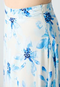 Gonna floreale in tessuto leggero con grandi fiori blu dai centri scuri, chiusura con zip laterale e silhouette fluida.