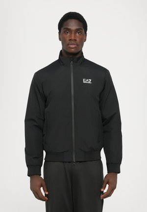 Giacca bomber nera con zip frontale, colletto alto, polsini e orlo elastici. Include un piccolo logo EA7 sul petto sinistro. Tessuto morbido.