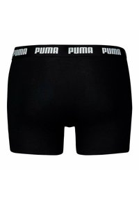 Boxer shorts neri con una cintura elastica morbida, caratterizzati dal logo PUMA in bianco. Il tessuto è liscio e presenta un design aderente.