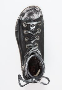 Black leather sandal with metallic silver laces wrapped around the ankle and eyelets, featuring a rounded toe and zipper on the side.