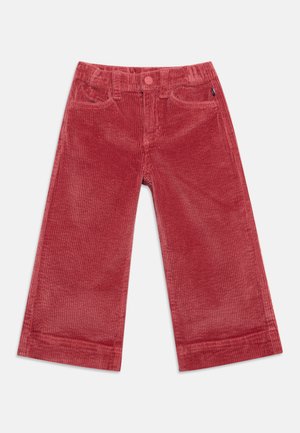 Pantalon large en velours côtelé rouge avec poches avant, passants pour ceinture et fermeture à bouton sur un fond uni.