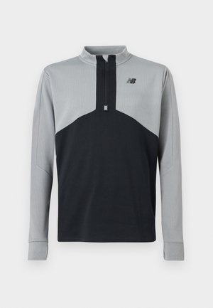 Langärmeliges Sportpullover mit Halbreißverschluss, grauer Oberkörper und Ärmel, schwarzer unterer Torso und einem kleinen New Balance Logo auf der Brust.