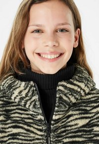 Fleece jack met een zwart en crème zebra-strijkpatroon, hoge kraag en ritssluiting. Zachte textuur en een relaxte pasvorm.