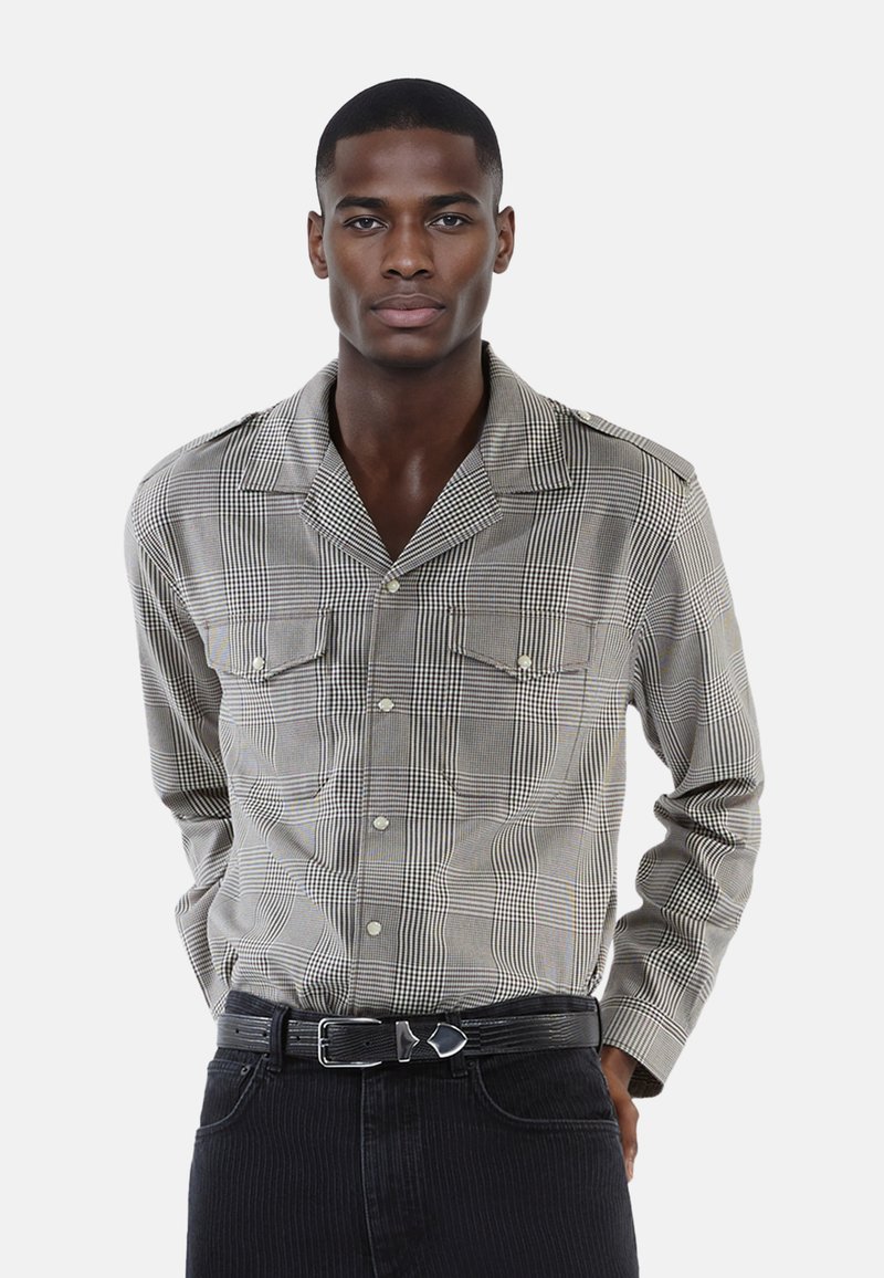 Camicia a maniche lunghe con modello a quadri in toni di grigio, caratterizzata da un collo a camicia, due tasche sul petto e abbinata a pantaloni scuri.