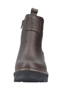 Bottine en cuir marron avec fermeture éclair latérale, couture avant visible, languette, semelle noire épaisse et écusson à logo embossé sur le devant.