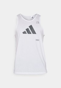 Bílý bezrukávový top vyrobený z bavlny, s velkým černým logem Adidas v síťovaném vzoru a malou nálepkou s nápisem "IMPOSSIBLE IS NOTHING."
