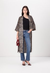 Robe stile kimono con stampa leopardata in tessuto leggero. Caratterizzato da maniche ampie e un design lungo e aperto. Abbinato a una maglietta nera e jeans skinny.