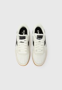 Λευκά αθλητικά παπούτσια με μαύρη πλαϊνή ρίγα, στρογγυλεμένη μύτη και διάτρητες λεπτομέρειες. Διαθέτουν λευκά κορδόνια και εξωτερική σόλα από καουτσούκ.