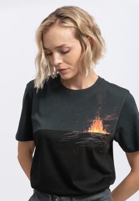 T-shirt nera in cotone con una grafica vivace di un fuoco e silhouette nella parte inferiore, con scollatura rotonda e maniche corte.