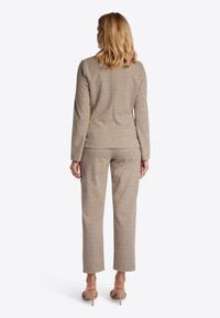 Blazer a scacchi e pantaloni coordinati in tonalità beige e marrone. Tessuto liscio con una vestibilità strutturata. Design minimalista con dettagli sottili.