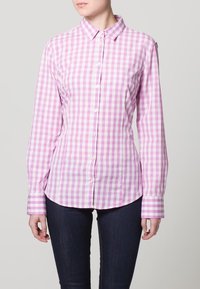 Långärmad skjorta med knappar i rosa och vit rutigt mönster, med krage och knappar fram. Tillverkad av ett slätt tyg.