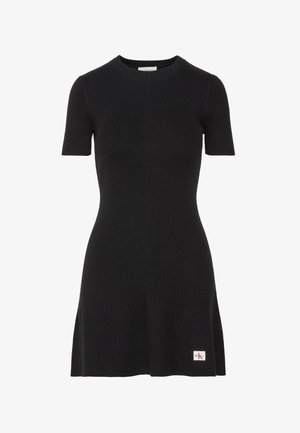 Juoda pūsta mezgimo trumpomis rankovėmis su apvalia iškirpte ir maža Calvin Klein logotipo dėmė šalia apačios kairėje pusėje.