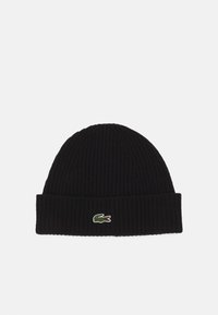 Svart ribbestrikket beanie med brettet mansjett og en liten grønn og rød Lacoste-logo på forsiden. Myk tekstur, tettsittende design.