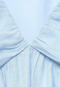 Light blue dress featuring a textured fabric with a v-neck design, gathered waist, and smooth draping. No visible patterns or hardware details.