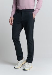 Zwarte dresspants van lichtgewicht stof, met een vlakke voorkant, model met zijzakken en subtiele stiksels.