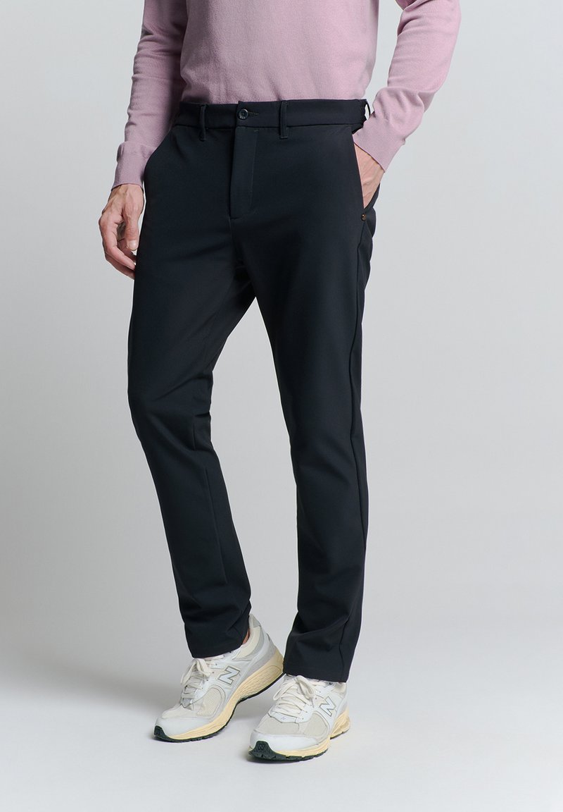 Zwarte dresspants van lichtgewicht stof, met een vlakke voorkant, model met zijzakken en subtiele stiksels.