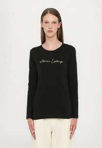 Black long-sleeve T-shirt made of cotton with a round neckline. Features gold "Armani Exchange" script across the chest. Simple and fitted design.