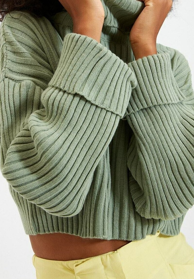 Maglione verde a coste con collo alto e maniche oversize, dotato di un design cropped e tessuto testurizzato.