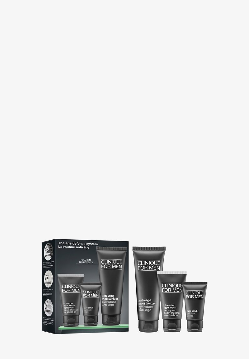Set Clinique For Men con idratante anti-età, detergente viso al carbone e scrub viso in tubetti neri accanto alla confezione del prodotto.