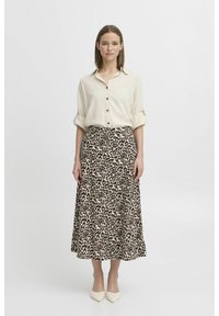 Helle beige Knopfleiste-Hemd mit hochgekrempelten Ärmeln, kombiniert mit einem knielangen Rock mit Leopardenmuster. Weiße spitze Pumps runden das Outfit ab.