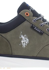 Gröna läder sneakers med svarta detaljer, som har en polospelare-logotyp, hexagonala ögla och en kontrasterande vit sula och snöre.