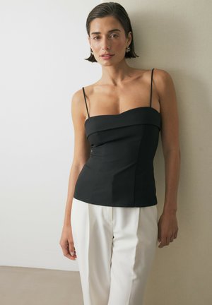 Zwarte, aansluitende zijden camisole met dunne spaghetti bandjes, met een gestructureerde corsage en een soepele textuur, gecombineerd met witte maatpakken.