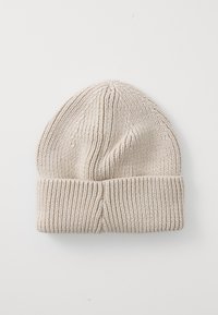 Bonnet en tricot beige avec un revers replié, fabriqué à partir d'un tissu doux présentant une texture côtelée et un design sans couture en haut.