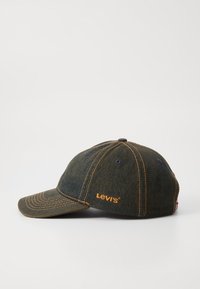 Denimska kapa za bejzbol v temno modri barvi z oranžnimi šivi. Značilnosti vključujejo ukrivljen rob in logotip izvezen na strani.