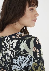 Blumenbluse mit schwarzem Grundton, verziert mit hellblauen, grünen und rosa Blumen, runder Ausschnitt und weichem Stoff mit glatter Textur.