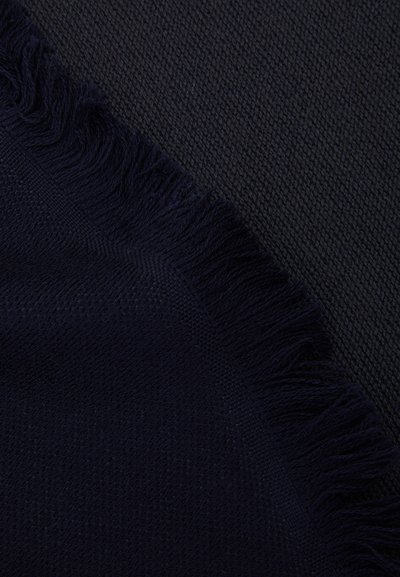 Tessuto intrecciato blu navy con una superficie texture, caratterizzato da un bordo frangiato. Il materiale appare morbido e accogliente con un motivo sottile.