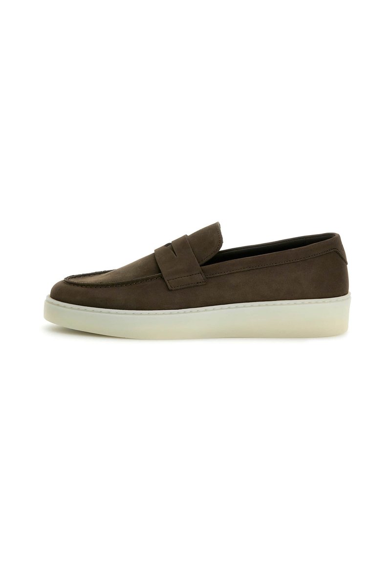 Zapatos de ante marrón tipo slip-on con una suela plana de goma blanca y un diseño cosido en la parte superior. Estilo de bajo perfil y minimalista.
