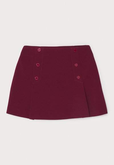 Burgundi spalvos mini sijonas su struktūrizuotu dizainu. Pasižymi dviem šoninėmis kišenėmis, dekoruotomis derančiais mygtukais. Lygus, tekstūruotas audinys.