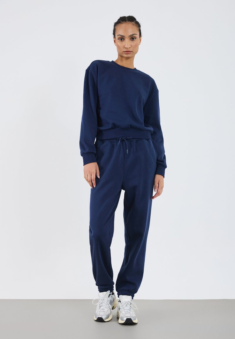 Navy sweatshirt and joggers made of soft fabric, featuring a crew neckline, ribbed cuffs, and an adjustable drawstring waistband.