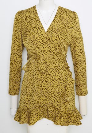 Robe portefeuille jaune avec des taches léopard marron, manches longues, ceinture à la taille et ourlet à volants sur un buste de mannequin blanc.