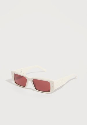Lunettes de soleil rectangulaires blanches avec des verres teintés de rose et des détails décoratifs sur les branches, sur un fond blanc.